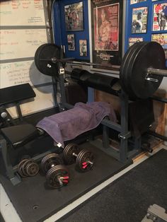 there is a bench and two dumbs in the gym area with posters on the wall