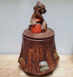 a small ceramic squirrel sitting on top of a tree stump with a basket in it's mouth