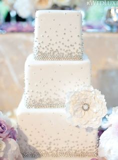 a three tiered white wedding cake sitting on top of a table next to flowers