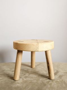 a wooden stool sitting on top of a carpeted floor