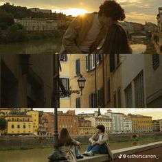 two people sitting on a bench in front of buildings and the sun setting behind them