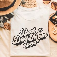 a t - shirt that says best dog mom ever on it next to sunglasses and other items