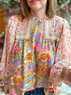 Look blooming fabulous in this Grace Multi-Floral Blouse! From the frill mock neck to the sheer bubble sleeves, this playful top will have you living your best floral fantasy. Plus, the smocked cuffs provide a flattering and comfortable fit. Get ready to brighten up the room! Relaxed fit. I am in the small. You can size down. Sizes: Small-Large 100% Rayon Follow tag instructions for washing. Feminine Flowy Smocked Top With Floral Print, Spring Floral Print Smocked Top With Puff Sleeves, Feminine Fall Smocked Top With Floral Print, Feminine Floral Smocked Top For Fall, Multicolor Summer Top With Smocked Cuffs, Summer Multicolor Top With Smocked Cuffs, Summer Multicolor Blouse With Smocked Cuffs, Spring Long Sleeve Peasant Top With Elastic Sleeves, Multicolor Balloon Sleeve Blouse For Spring