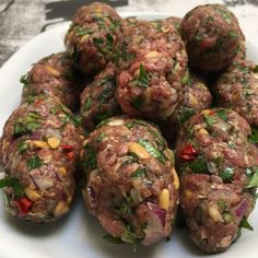 a white plate topped with meatballs covered in toppings