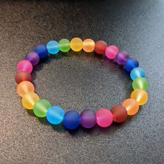 This delightful bracelet is made with 8mm round frosted glass beads in a rainbow of colors. It is great for stacking or can be worn on its own. It is approximately 7 inches long, which fits an average sized wrist. Please measure wrist to ensure proper fit. Great care has been taken to ensure that your bracelet has been assembled securely. However, please keep in mind the nature of elastic cord and take care not to over-stretch your bracelet and risk breakage. To extend the life of your bracelet and keep the beads from fading, avoid contact with water, sweat, chemicals, or prolonged direct sunlight. Please message me with any questions. To see other bracelet options, check out my full store: https://www.etsy.com/shop/shopcraftyoctopus/ Make Clay Beads, Pride Bracelet, Glass Bead Bracelet, Kawaii Jewelry, Rainbow Glass, Bead Ideas, Rainbow Bracelet, Bangle Bracelets With Charms, Bracelet Ideas