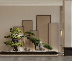 a bonsai tree is displayed in front of a wall with art work on it