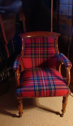 a red plaid chair sitting on top of a carpeted floor next to a mirror