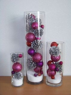 three glass vases filled with ornaments on top of a table