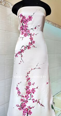 a white dress with pink flowers painted on the front and back, sitting on a mannequin