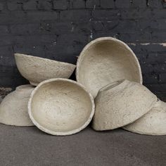 several white bowls stacked on top of each other in front of a black brick wall