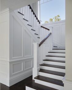 a white staircase with black railing and wood flooring