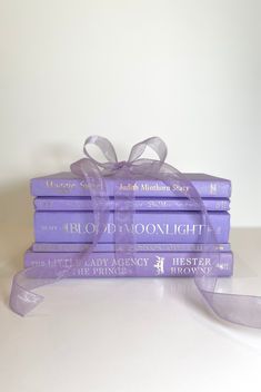 a stack of purple books with a ribbon tied around the book ends on top of each other