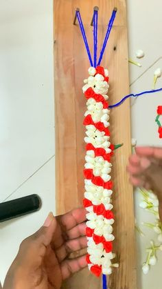 two hands are working on an american flag flower garland with red, white and blue flowers