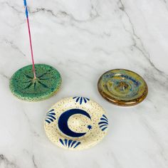 three ceramic dishes sitting on top of a white marble counter next to a candle holder