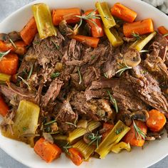 a white bowl filled with meat, carrots and celery on top of a table