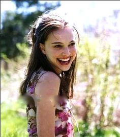 a young woman is smiling and standing in the grass with her hands on her hips