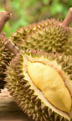 two pieces of durian fruit sitting on top of a wooden table next to each other