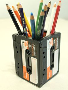 there are many pencils in the holder on the table, and one is made from an old cassette