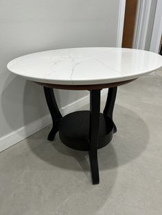 a white marble table with black legs in a living room or dining room area next to a door