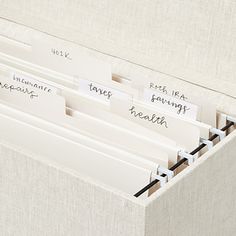 three file folders with labels on them sitting in a linen box next to each other