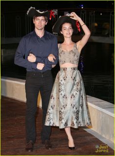 a man standing next to a woman in a dress on a wooden deck at night