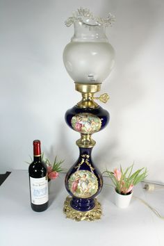 a wine bottle is next to a vase with flowers on it and a flower pot