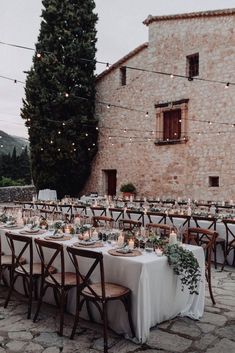 a long table with candles and greenery is set up outside for an outdoor dinner