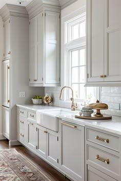 a kitchen with white cabinets and gold hardware on the countertops, along with a rug