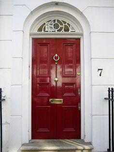 a red door is in front of a white building