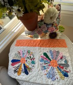 a quilted table runner with flowers and a potted plant