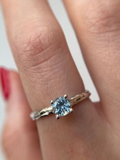 a woman's hand holding a ring with a blue topazte in it