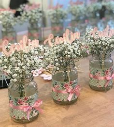 four vases filled with baby's breath flowers on top of a wooden table