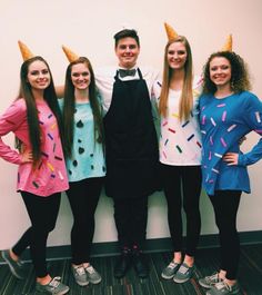 three girls and one boy are standing in front of a wall with ice cream cones on their heads