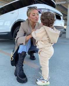 a woman kneeling down next to a small child