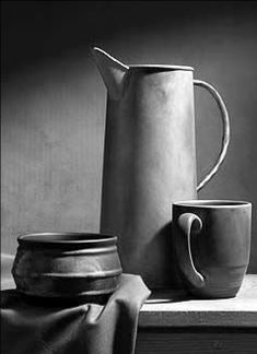 black and white photograph of two coffee pots, one with a mug