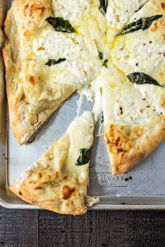 a pizza sitting on top of a pan covered in cheese and spinach toppings