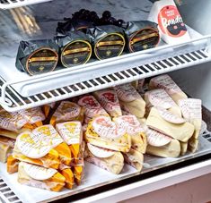 several different types of cheeses on display in a store case, including bagels and crackers