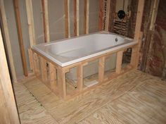 a bathtub in the middle of a room being built with wooden framing around it