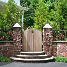 a wooden gate in the middle of a stone wall with steps leading up to it