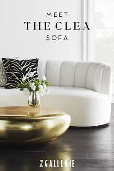 a white couch sitting next to a table with flowers on it and the words meet the clea sofa