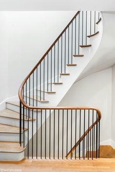 a white staircase with wooden handrails and black railing on the bottom floor in an empty room