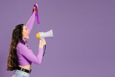 a woman holding a megaphone up to her head with a purple ribbon around her neck