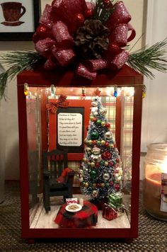 a small christmas tree in a red box with lights and decorations on it's sides