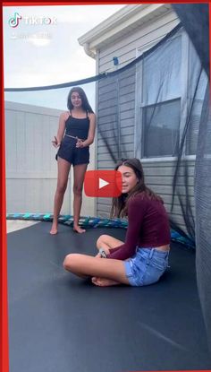 two women are sitting on a trampoline and one is talking to the camera