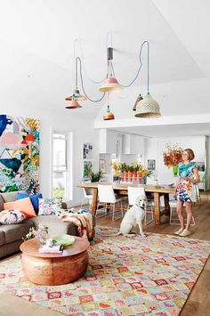 a woman standing next to a dog in a living room filled with furniture and decor