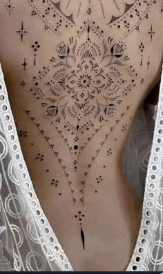 a woman's back with an intricate tattoo design on her lower back and side