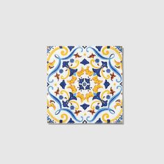 a blue and yellow square tile with an ornate design on the bottom, surrounded by swirls