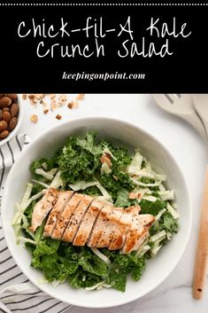 a white bowl filled with chicken, lettuce and nuts on top of a table