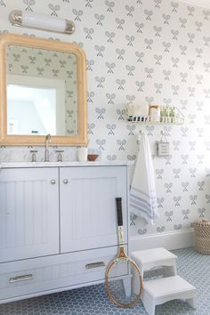 a bathroom with a sink, mirror and racket on the floor in front of it