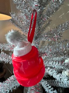 a red and white christmas ornament sitting on top of a silver tinsel tree